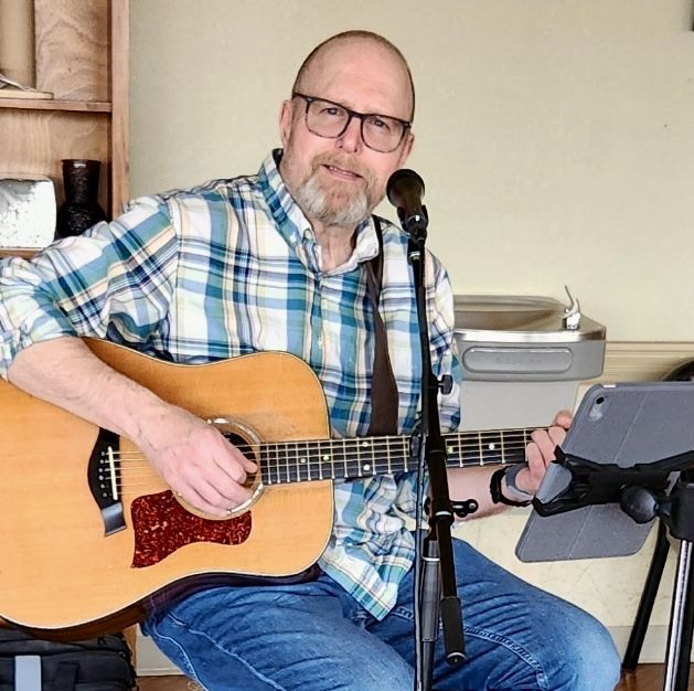 Chris Pawola singing and playing an acoustic guitar